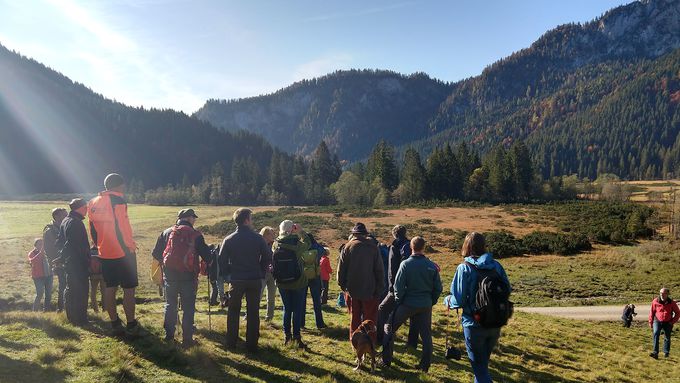 Menschengruppe steht in einer Landschaft vor Bergen